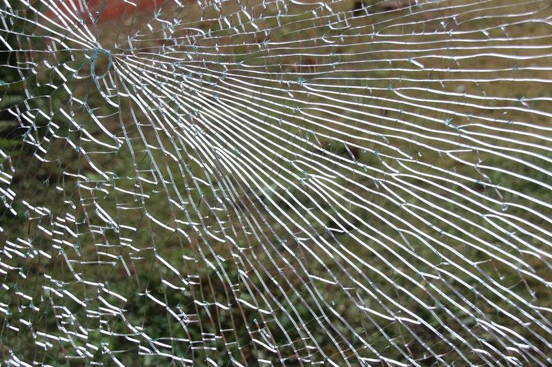 Krossad glasruta med sprickor som går ut från träffpunkten
