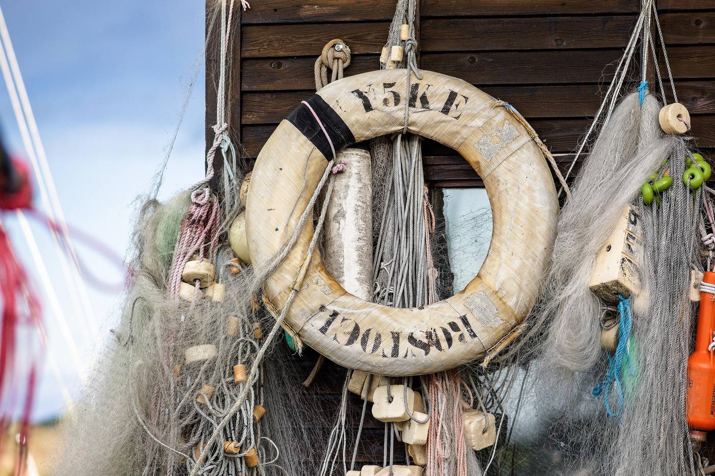 Livboj och fisknät som hänger på en sjöbodsvägg