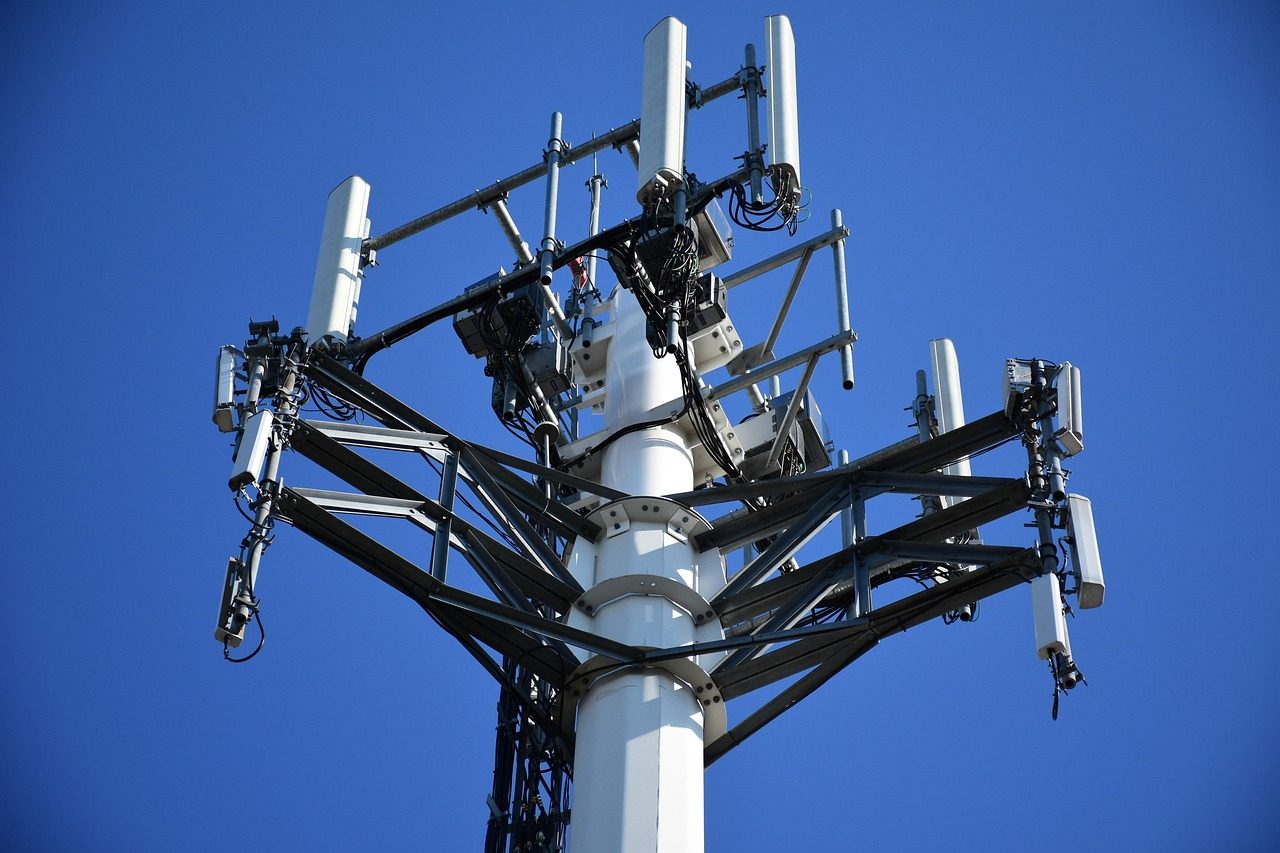 Mobilmast med antenner mot blå himmel